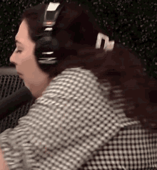 a woman wearing headphones is sitting in front of a microphone in a studio .