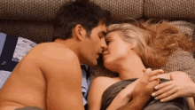 a man and woman kissing on a couch with the man holding the woman 's hand