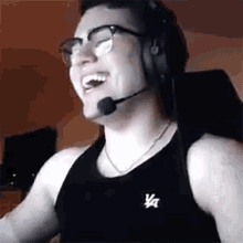 a man wearing glasses and headphones is laughing while wearing a black tank top .