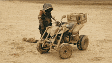 a man is standing next to a muddy atv with boxes on the back of it