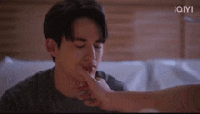 a man is laying on a bed and a woman is putting her hand on his face .