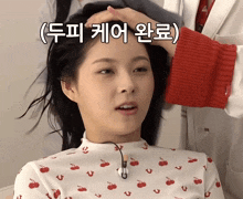 a woman in a red and white sweater with cherries on it is getting her hair blow dried