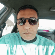 a man in a car wearing sunglasses and a sweater