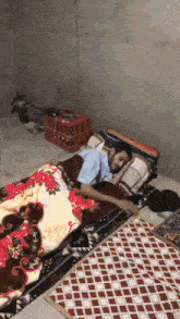 a man laying on a bed with a blanket that has a floral pattern on it