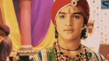 a close up of a man wearing a turban and jewelry .