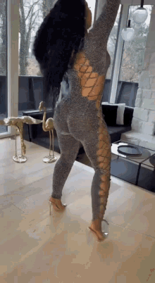 a woman in a jumpsuit is standing in a living room .