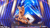 two men are performing on a stage with nbc written on the bottom