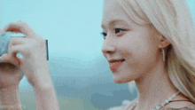 a blonde woman is taking a picture with a camera .