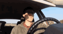 a man wearing glasses is driving a car with the sun shining on his face