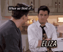 two men are talking in a kitchen and one of them has eliza written on his shirt