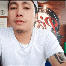 a man wearing a hat and a white shirt with a tattoo on his arm