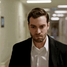 a man with a beard wearing a black suit and white shirt