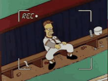 a cartoon of homer simpson sitting on a bench in a dugout being recorded