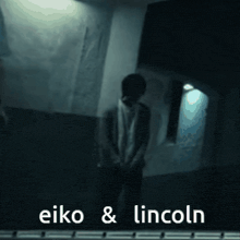 a man is standing in a dark room with the words eiko & lincoln behind him