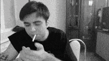 a black and white photo of a man smoking a cigarette .