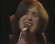 a woman with long hair is singing into a microphone .
