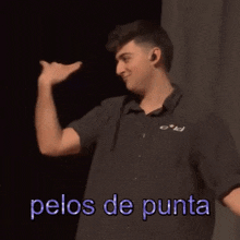 a man in a black shirt is holding a piece of paper and the words pelos de punta are above him .