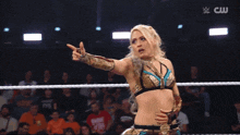 a woman in a wrestling ring with a cw logo on the bottom
