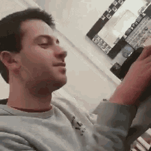 a man is sitting on a couch in a living room with his eyes closed and a mirror in the background .