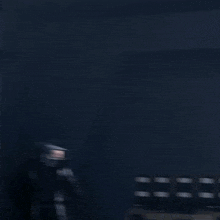 a man in a black coat is holding a camera in a dark room