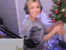 a woman wearing headphones stands in front of a microphone and a christmas tree