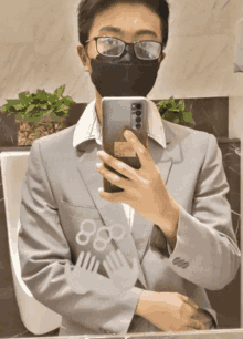 a man wearing glasses and a mask takes a picture of himself in the mirror