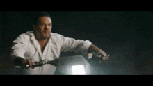 a man wearing a white shirt is riding a motorcycle at night