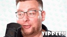 a man with glasses and a beard is singing into a microphone and the word yippee is on the bottom right
