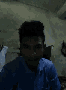 a man in a blue shirt is taking a selfie in a dark room