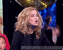 a woman in a black jacket stands in front of a disco ball with the words operationfanclublarafabian written on the bottom