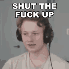 a young man wearing headphones with the words `` shut the fuck up '' written on it .