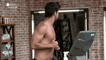 a shirtless man is running on a treadmill in front of a brick wall that says playplus