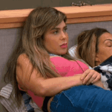 a woman in a pink tank top is laying on another woman 's lap on a couch .