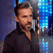 a man with a beard is standing in front of a screen that says supertalent