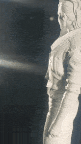 a white statue of a man in a jacket with a cross on it