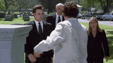 a man in a white shirt shakes hands with another man in a black suit