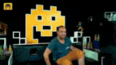 a man is sitting on a couch in front of a pixelated wall with a tetris logo