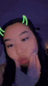 a close up of a woman making a funny face with neon lights on her head .