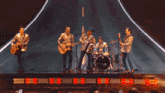 a group of men are playing guitars and drums on stage