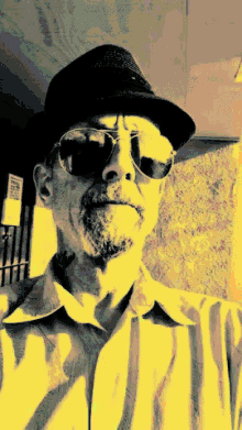 a man wearing sunglasses and a hat is standing in front of a sign that says " no smoking "