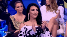 a woman in a polka dot dress applauds in front of a sign that says #gfvip on it