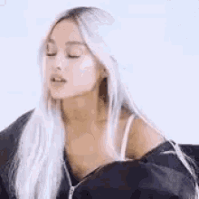 ariana grande is wearing a black jacket and a white top .