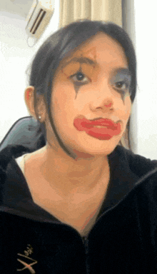a woman is wearing a clown costume with red lips and a black jacket .