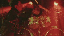 a man playing drums in a dark room with a red light behind him