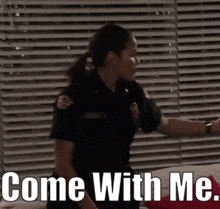 a woman in a police uniform is standing in front of a window with the words come with me written below her
