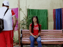 a woman in a red shirt sits on a bench