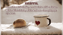 a cup of coffee with a heart on it sits next to a piece of bread