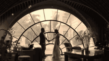 a bride and groom standing in front of a large window
