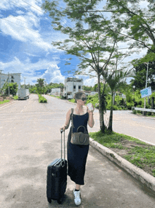 a woman walking down a street with a suitcase and a sign that says ' paradise '