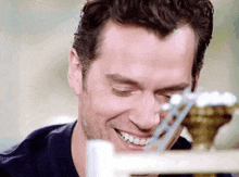 a close up of a man 's face smiling and looking at a toy .